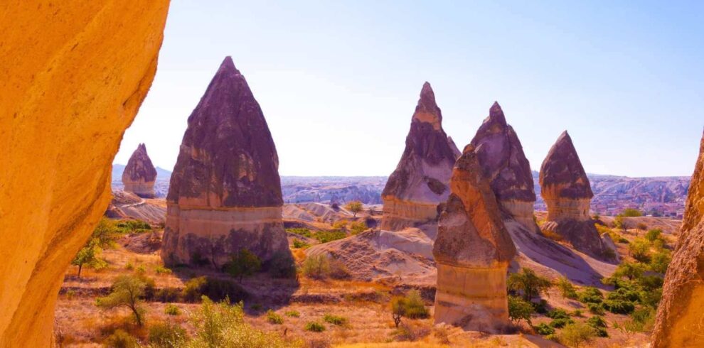 Unique conical rock formations known as fairy chimneys in Cappadocia, Turkey, under bright sunlight and a clear sky.