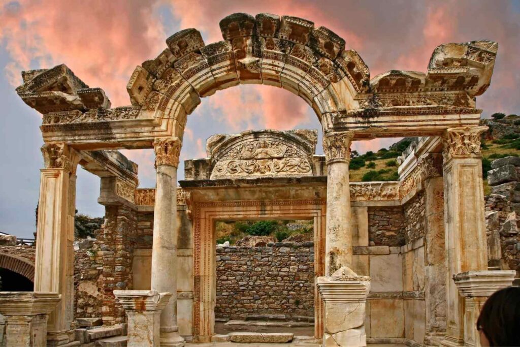 The ancient Temple of Hadrian in Ephesus, Turkey, featuring detailed stone carvings and arched columns at sunset.