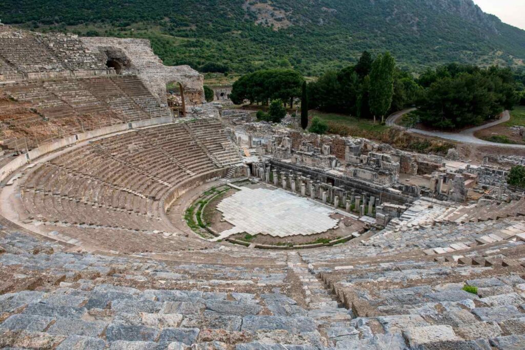 Ancient Grand Theater of Ephesus in Turkey, featuring tiered stone seating and a large stage area surrounded by ruins.