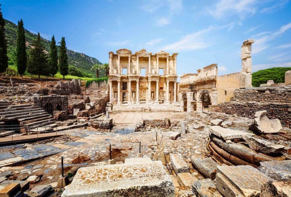 The ruins of the Celsus Library in Ephesus, Turkey, with towering columns and stone carvings under a bright sky.