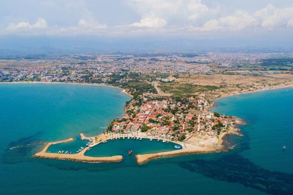 Aerial view of the coastal town of Side, Turkey, featuring a peninsula, marina, and surrounding turquoise waters.