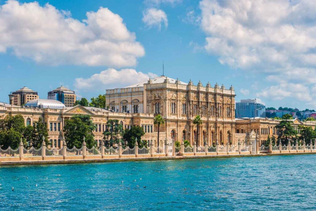 Exterior of Dolmabahçe Palace in Istanbul, situated by the Bosphorus under a partly cloudy sky.