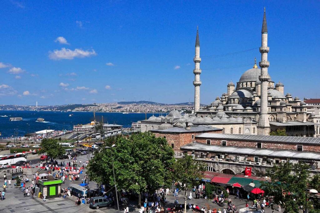 A stunning view of Istanbul featuring a grand mosque with tall minarets, busy streets, and the Bosphorus in the background.