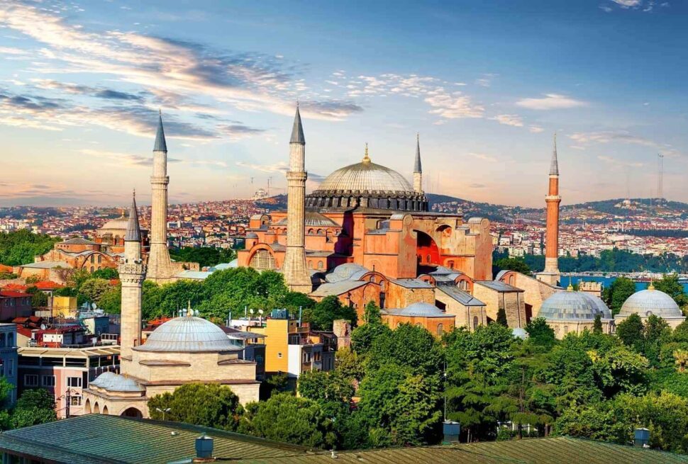 Aerial view of Hagia Sophia in Istanbul with its domes and minarets, surrounded by the cityscape under a cloudy sky.