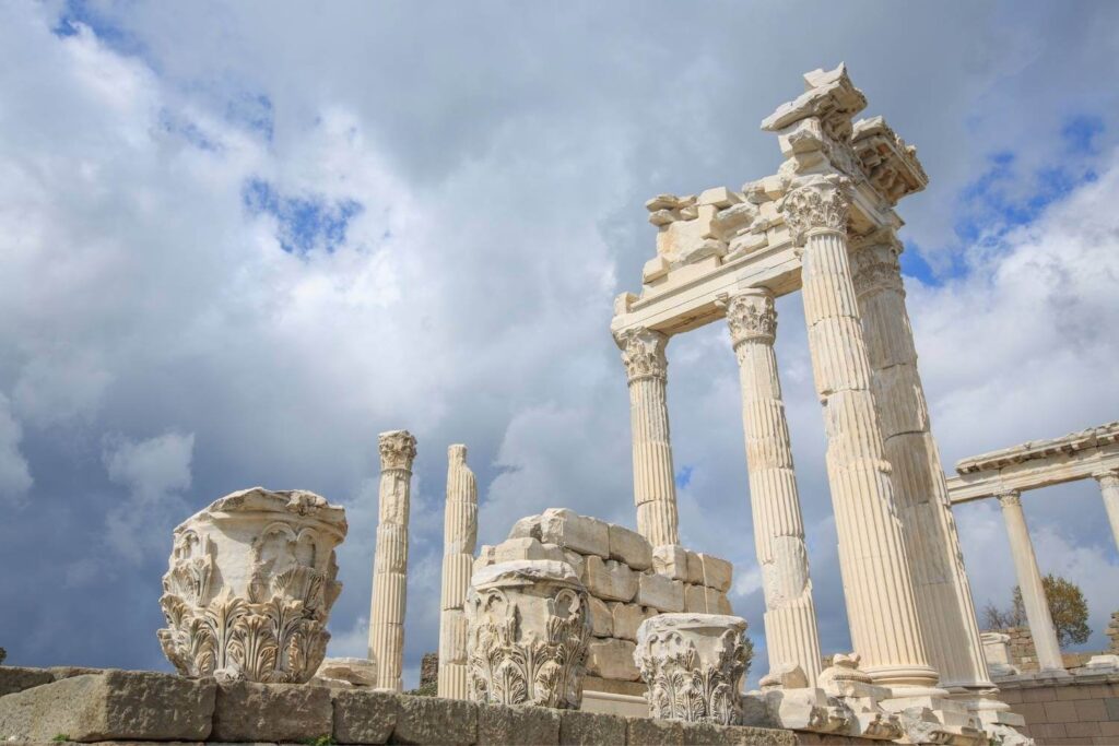 Ruins of the Temple of Trajan in Pergamon, Turkey, with ornate marble columns against a cloudy sky.